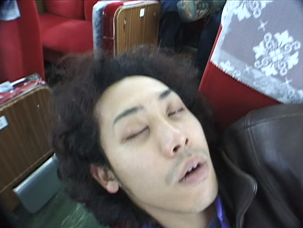 列車内でよこになって眠る大泉